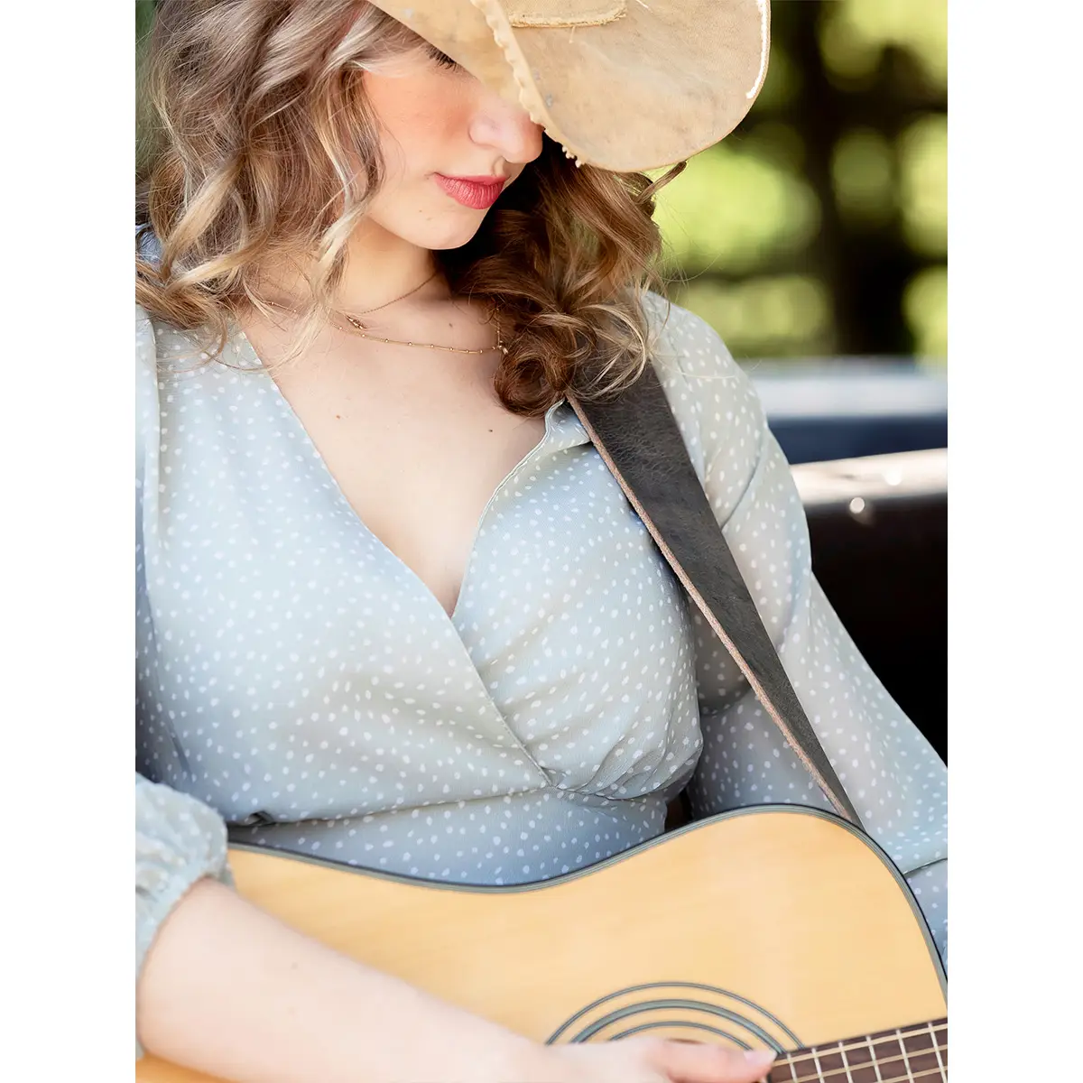 Model wearing the grey guitar strap on an acoustic guitar.