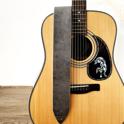 Stone Grey Distressed Leather Guitar Strap hanging over an acoustic guitar.